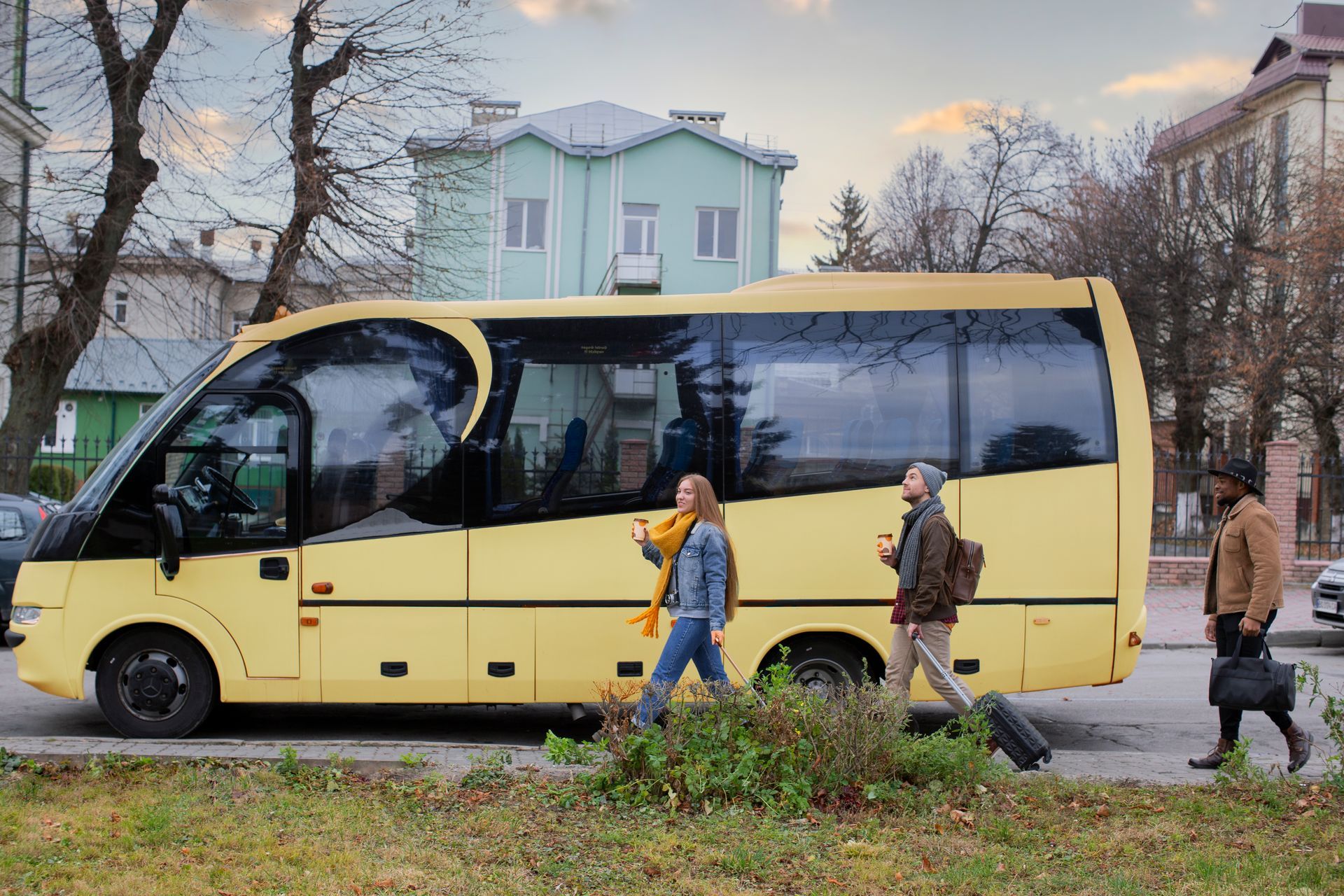 Yellow minibus parked on a street while three people walk past in a residential area.