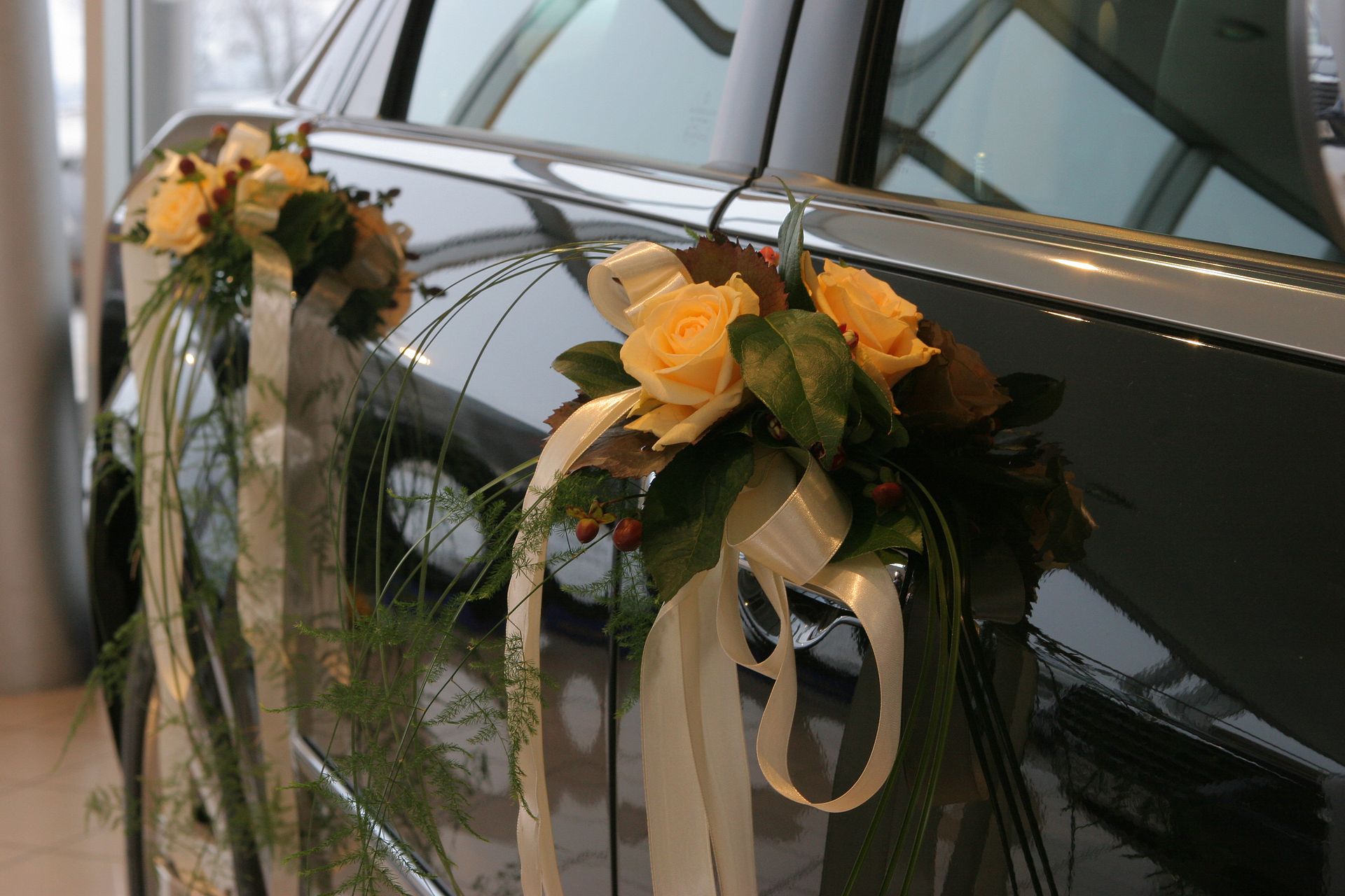 Car door decorated with cream roses and ribbons.