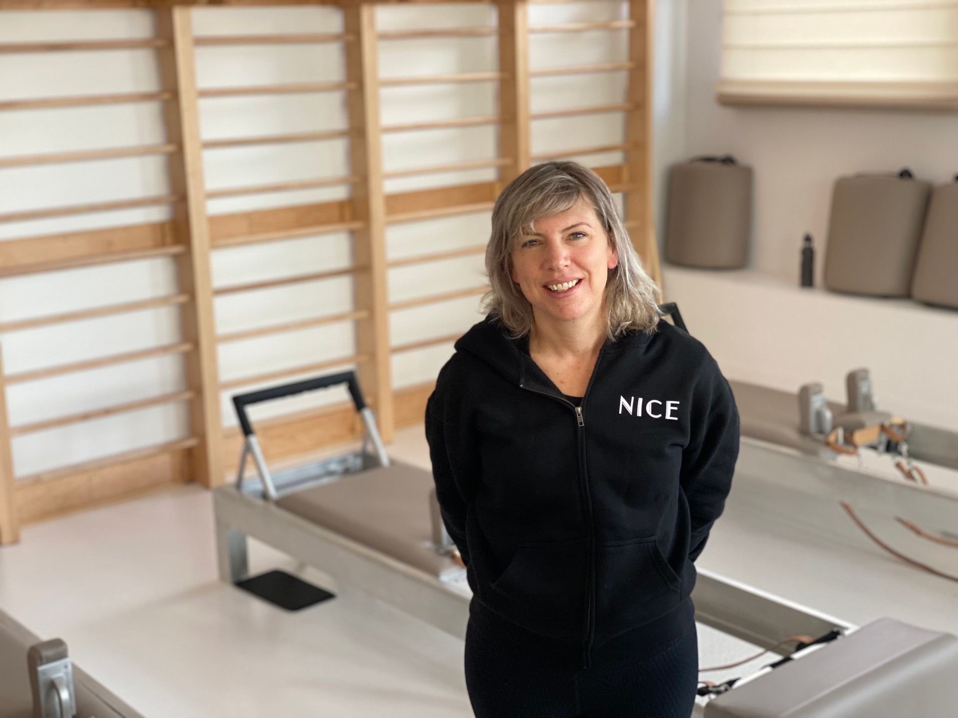 Woman in workout outfit standing in a room with pilates equipment