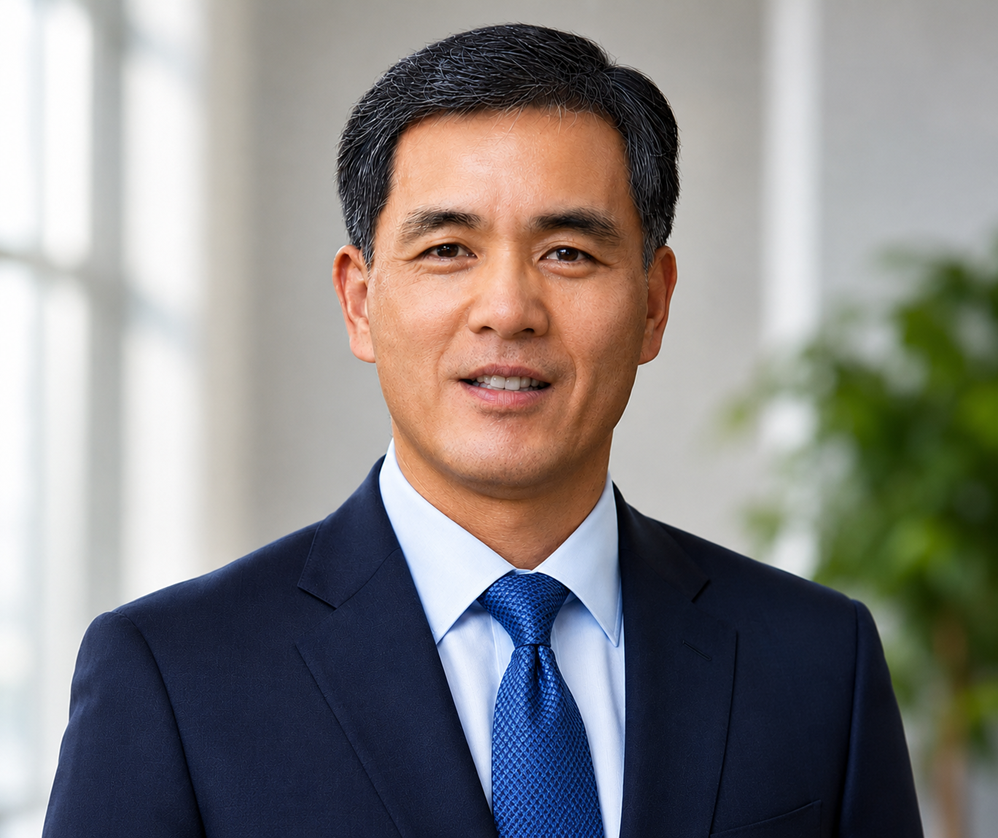 A man in a blue suit and red tie is standing in front of a window.