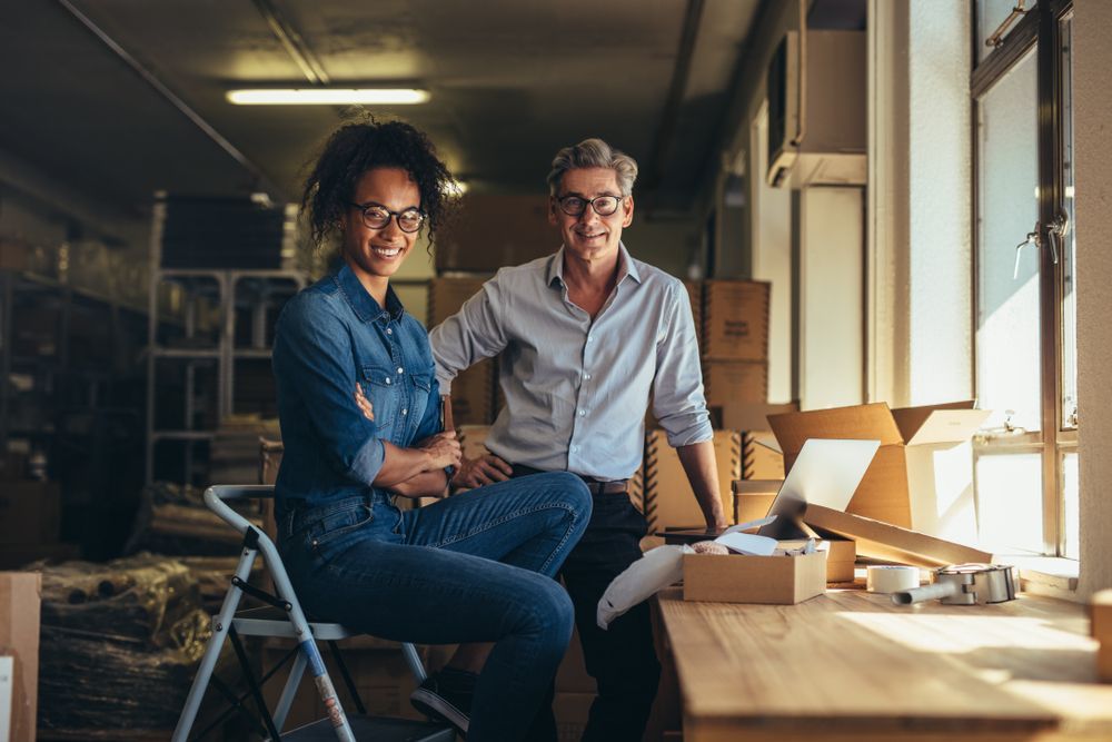 A man and a woman are sitting on a table in a warehouse.