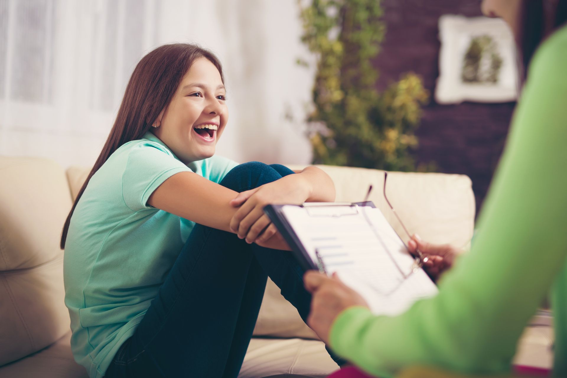 Smiling woman sitting on a couch during a counseling conversation with a clipboard nearby