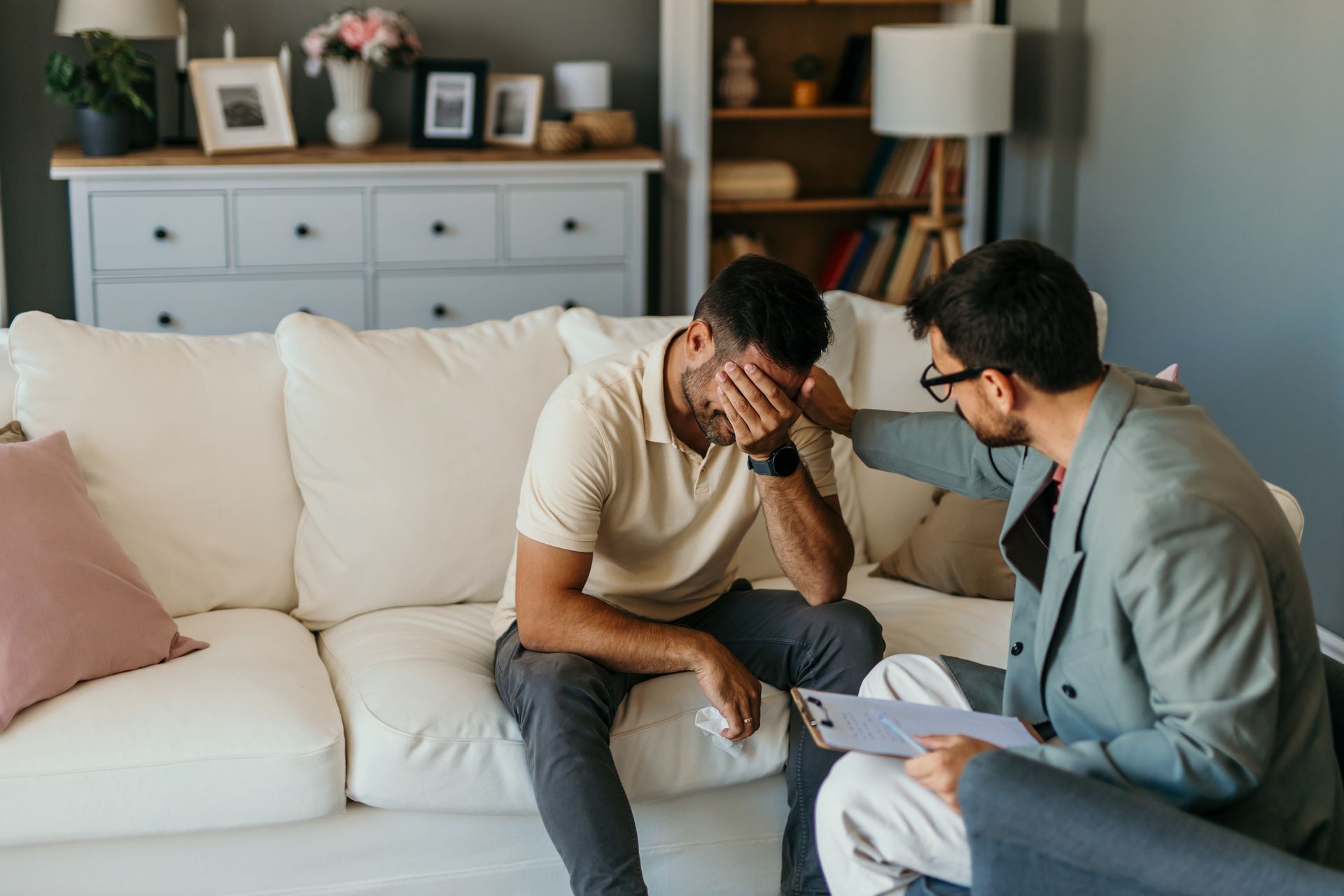 Therapist comforting a distressed client on a couch during a counseling session Therapist comforting a distressed client on a couch during a counseling session