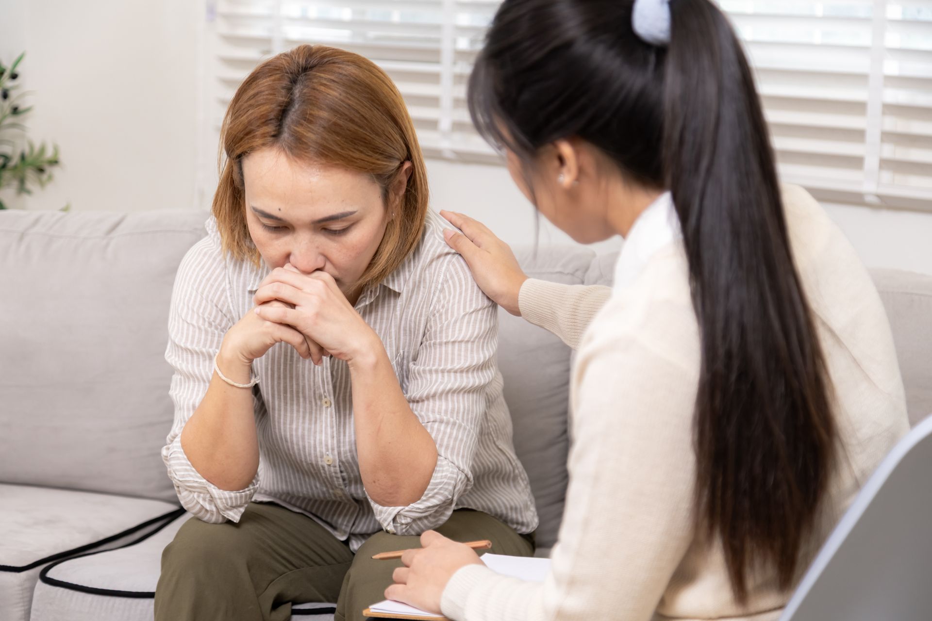 Two women talking on a couch, one consoling the other who looks upset. Two women talking on a couch, one consoling the other who looks upset.