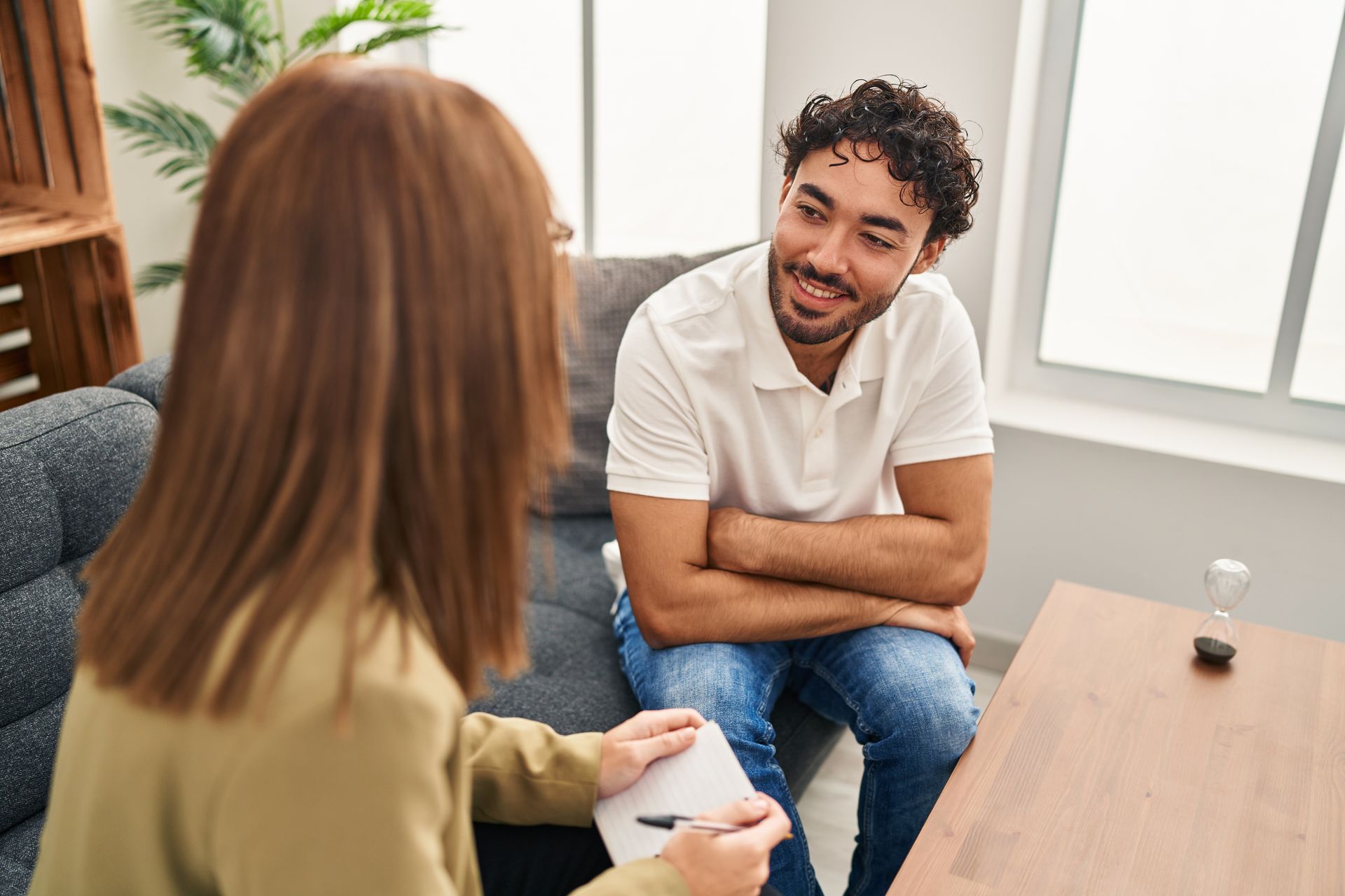 Two people talking in a bright office, one smiling while seated across a table.