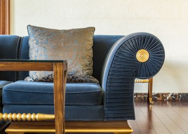 Blue sofa with patterned pillow and rounded armrest in a bright living room