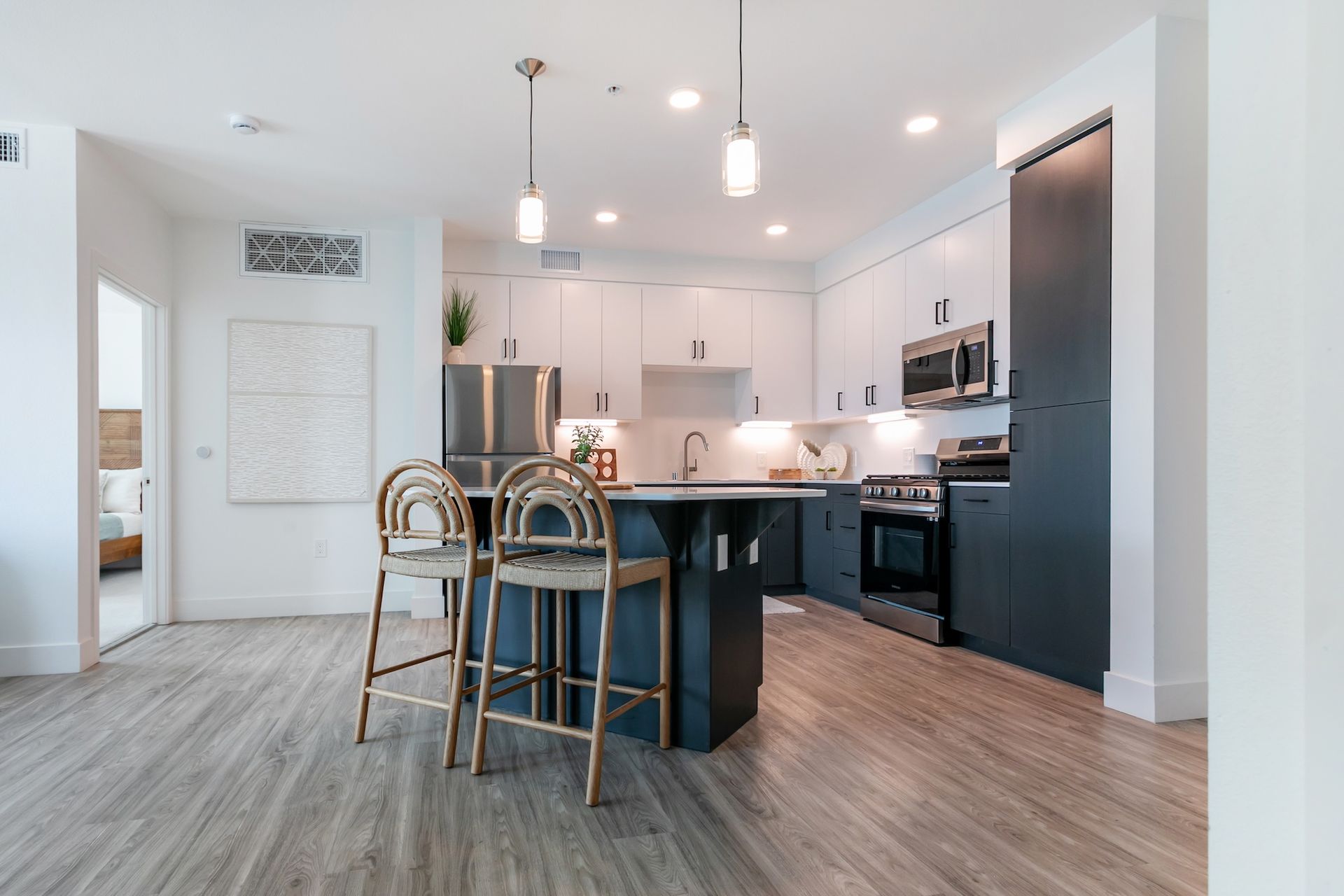 Modern kitchen with black and white cabinets, island, and stainless steel appliances.
