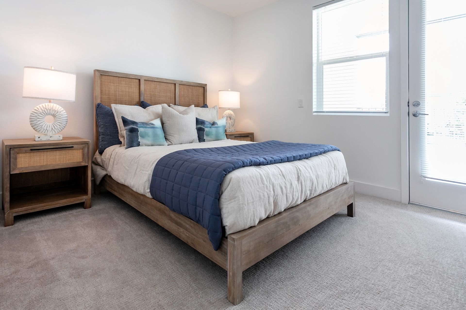 Bedroom with a wooden bed, white walls, and light gray carpet. Blue and white bedding.