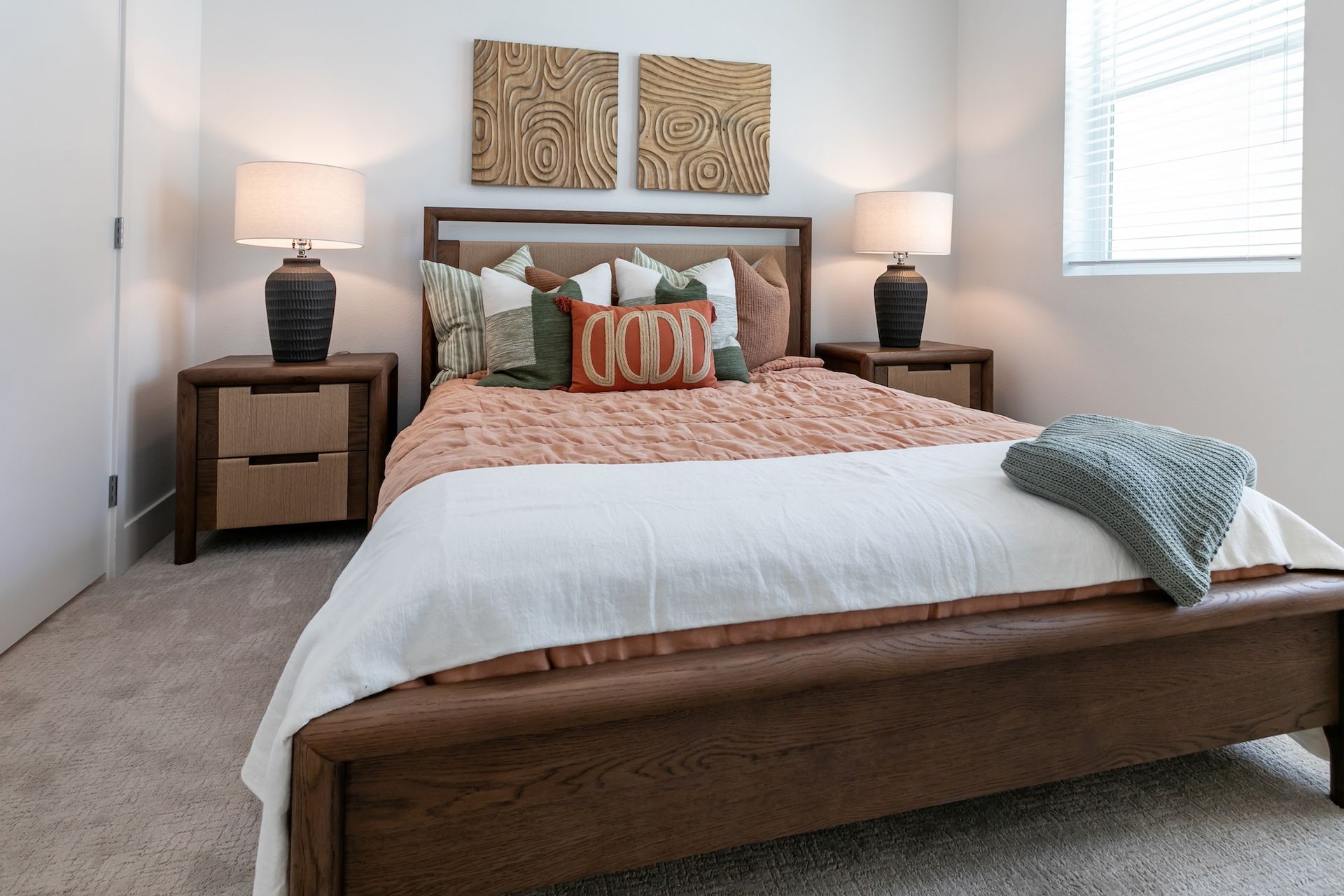 Bedroom with a wooden bed, nightstands, lamps, and decorative pillows.