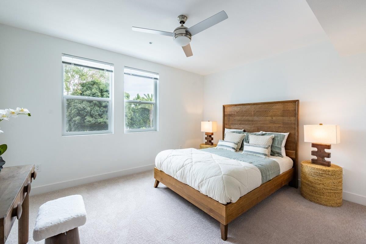 Bedroom with a wooden bed, white bedding, and a rustic wooden headboard. Two windows let in natural light.