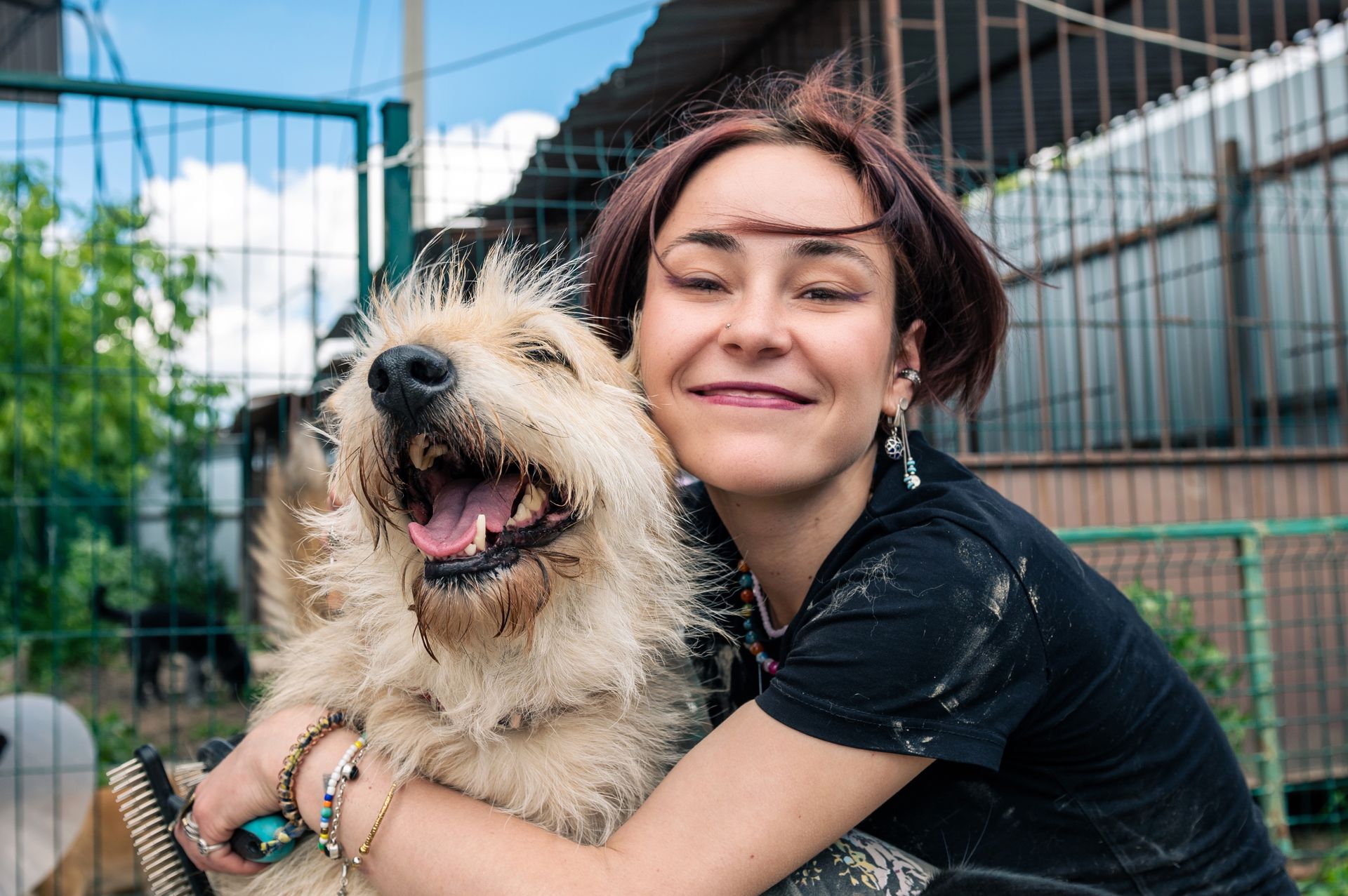 A smiling woman embraces a dog outdoors by dog boarding.