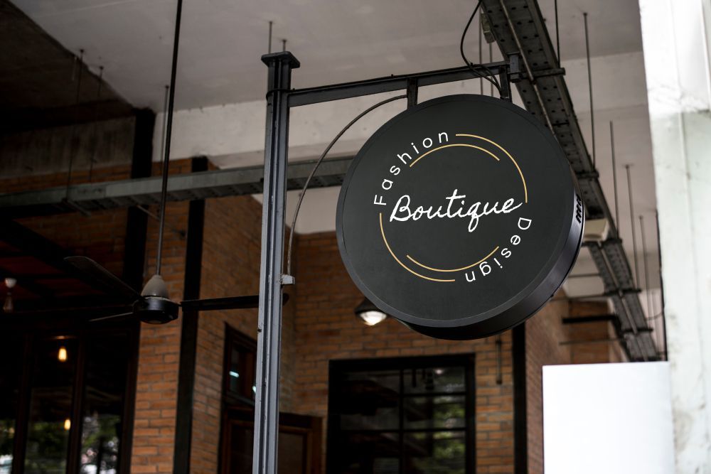 A Boutique Sign Is Hanging From A Pole Outside Of A Building — JW Signs and Designs In Cairns, QLD