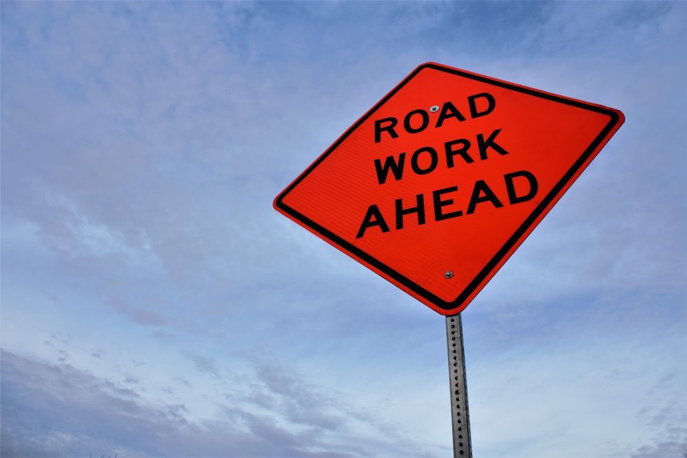 An Orange Road Work Ahead Sign And Blue Sky Background — JW Signs and Designs In Mount Isa, QLD