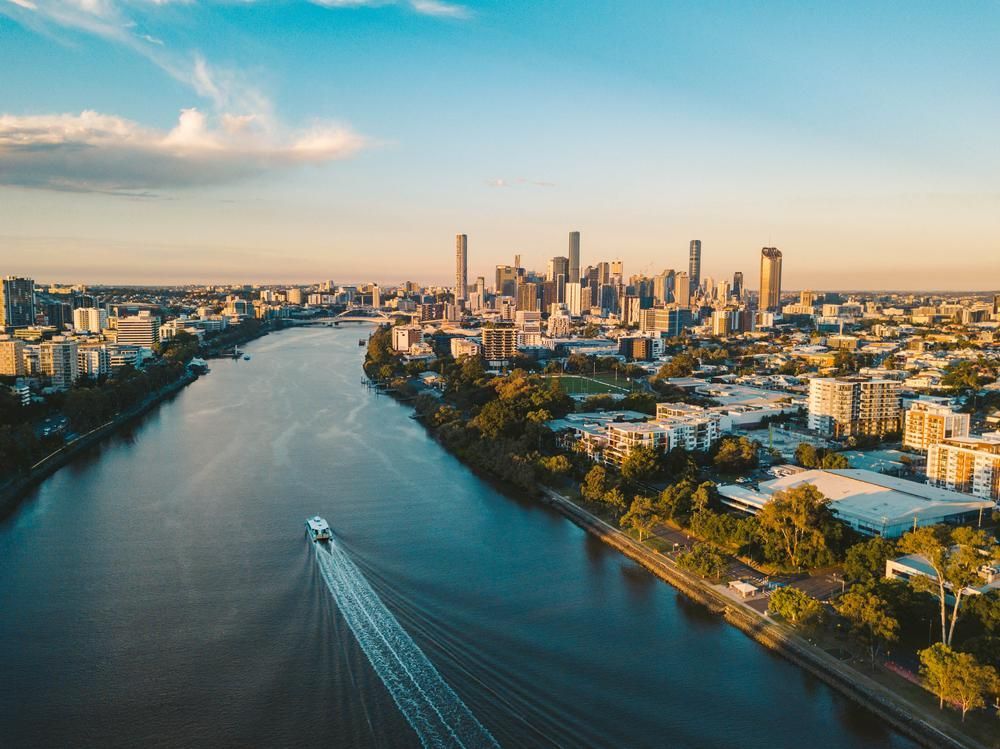 An Aerial View Of A River With A City In The Background And A Boat In The Foreground — JW Signs and Designs In Brisbane, QLD