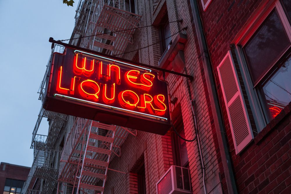 A Neon Sign For Wines Liquors Hangs From The Side Of A Building — JW Signs and Designs In Gladstone, QLD