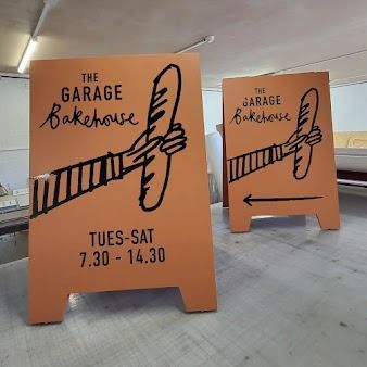 Two Signs For The Garage Bakehouse Are Sitting On A Table — JW Signs and Designs In Mount Isa, QLD