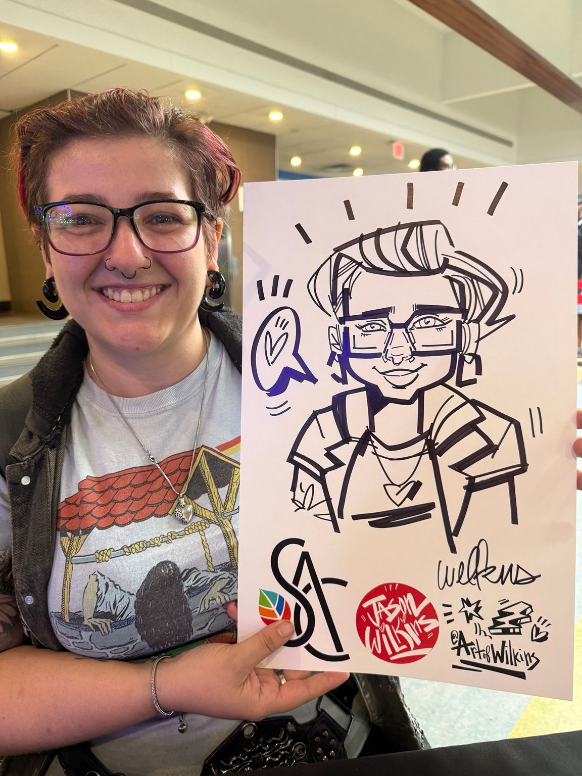 Fleming College guest with short red hair and glasses holding their personalized live caricature by Jason Wilkins.