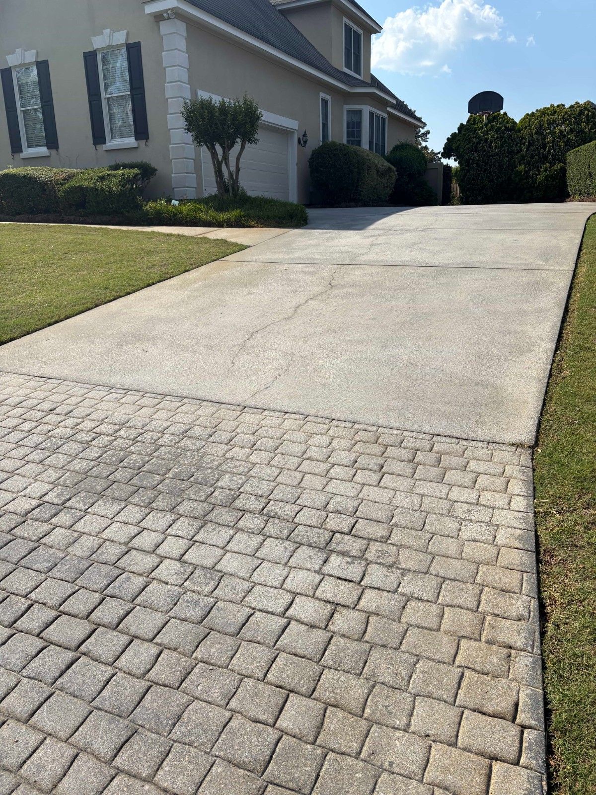 Residential driveway with a paver section leading up to a house on a sunny day