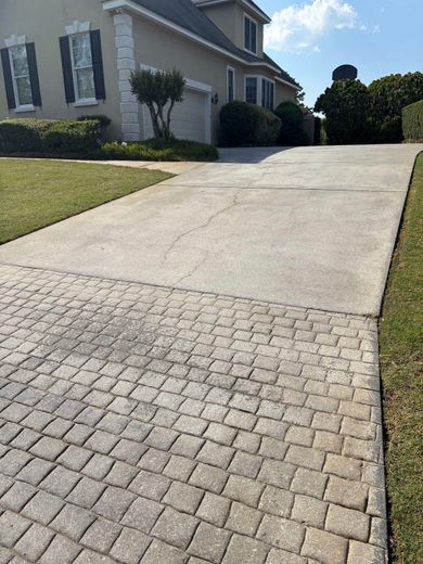 Residential driveway with a paver section leading up to a house on a sunny day