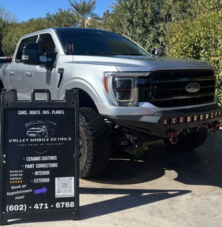 White pickup truck parked outdoors with a black business sign for car and truck accessories in front