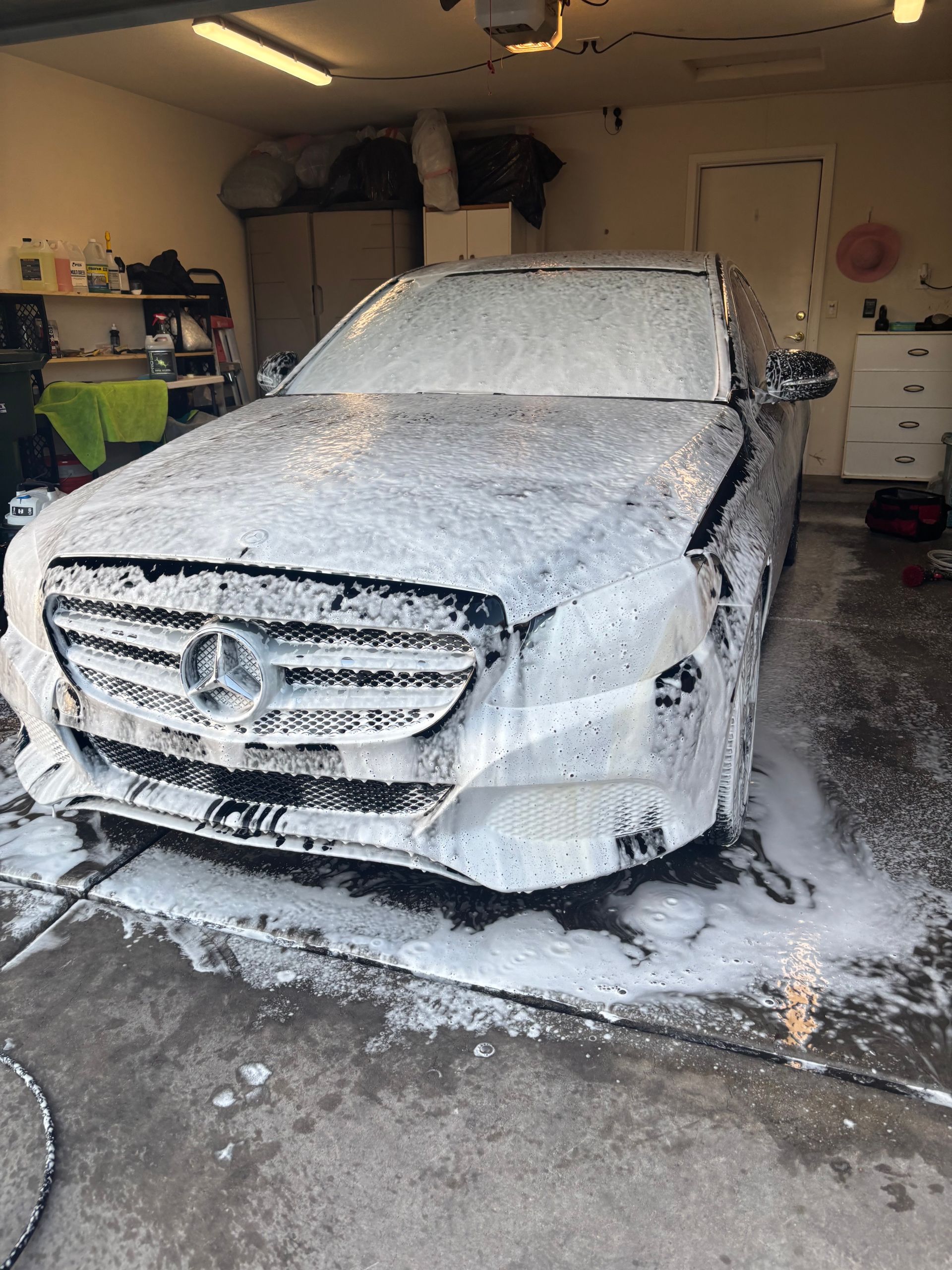 Foam-covered Mercedes-Benz SUV in a garage, with soap suds on the floor and walls.