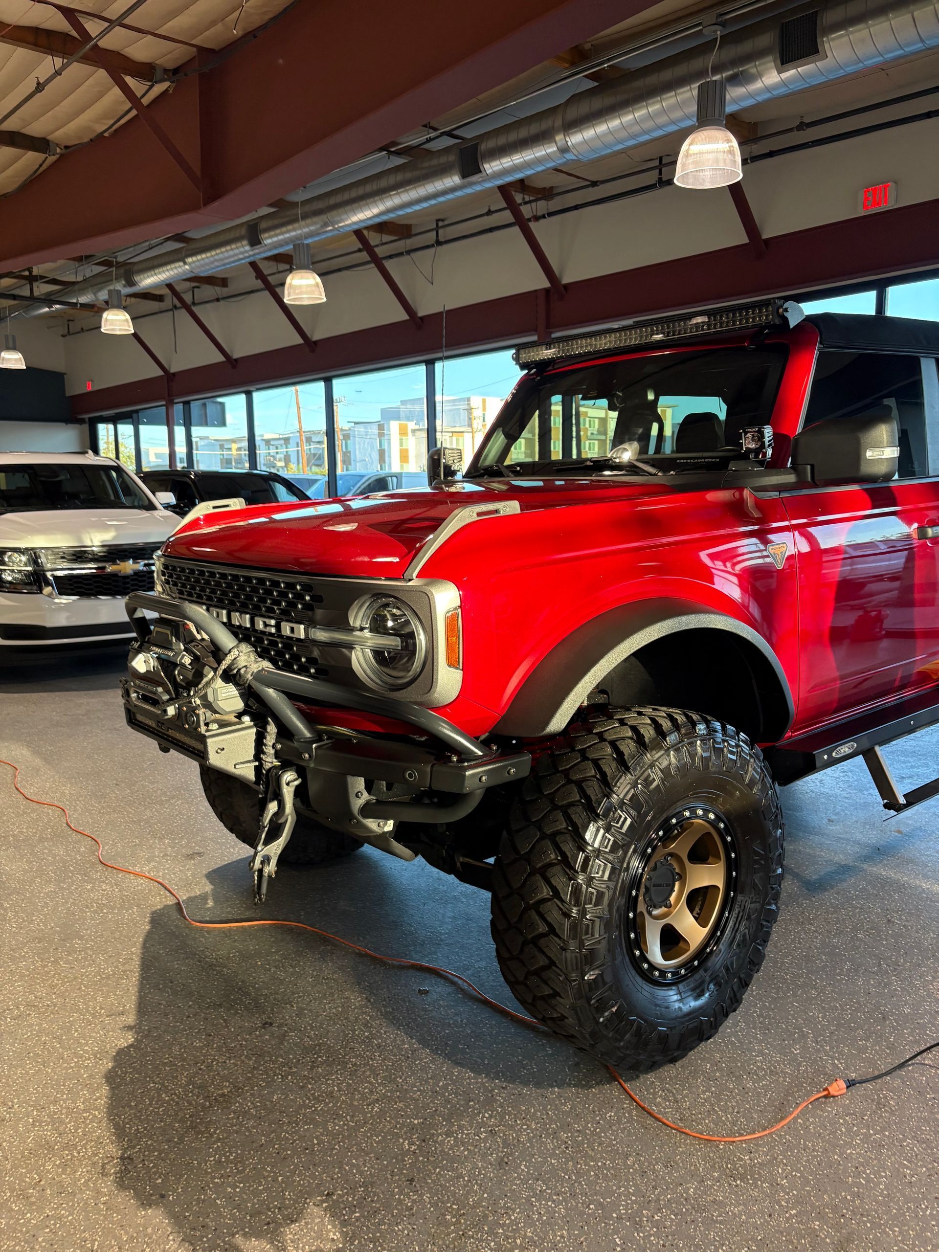 Bright red off-road Bronco with large tires on display in a showroom