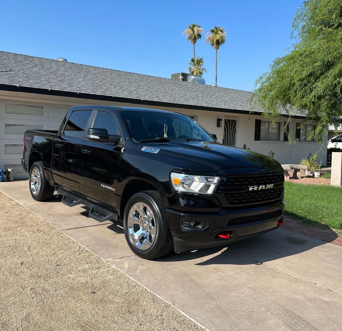 Black RAM pickup truck parked in a suburban driveway on a sunny day