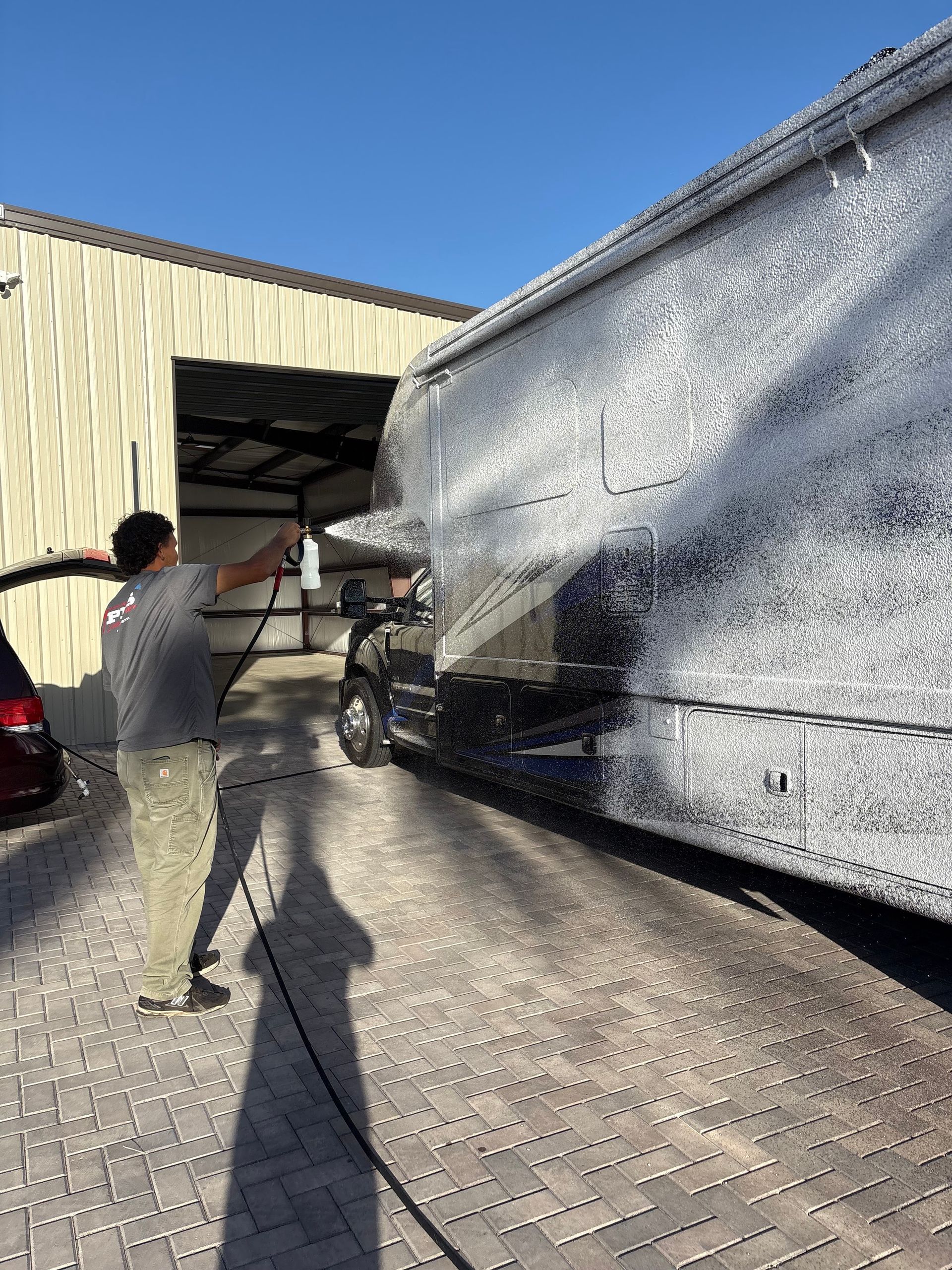 Person guiding a large white truck into a warehouse loading bay on a sunny day