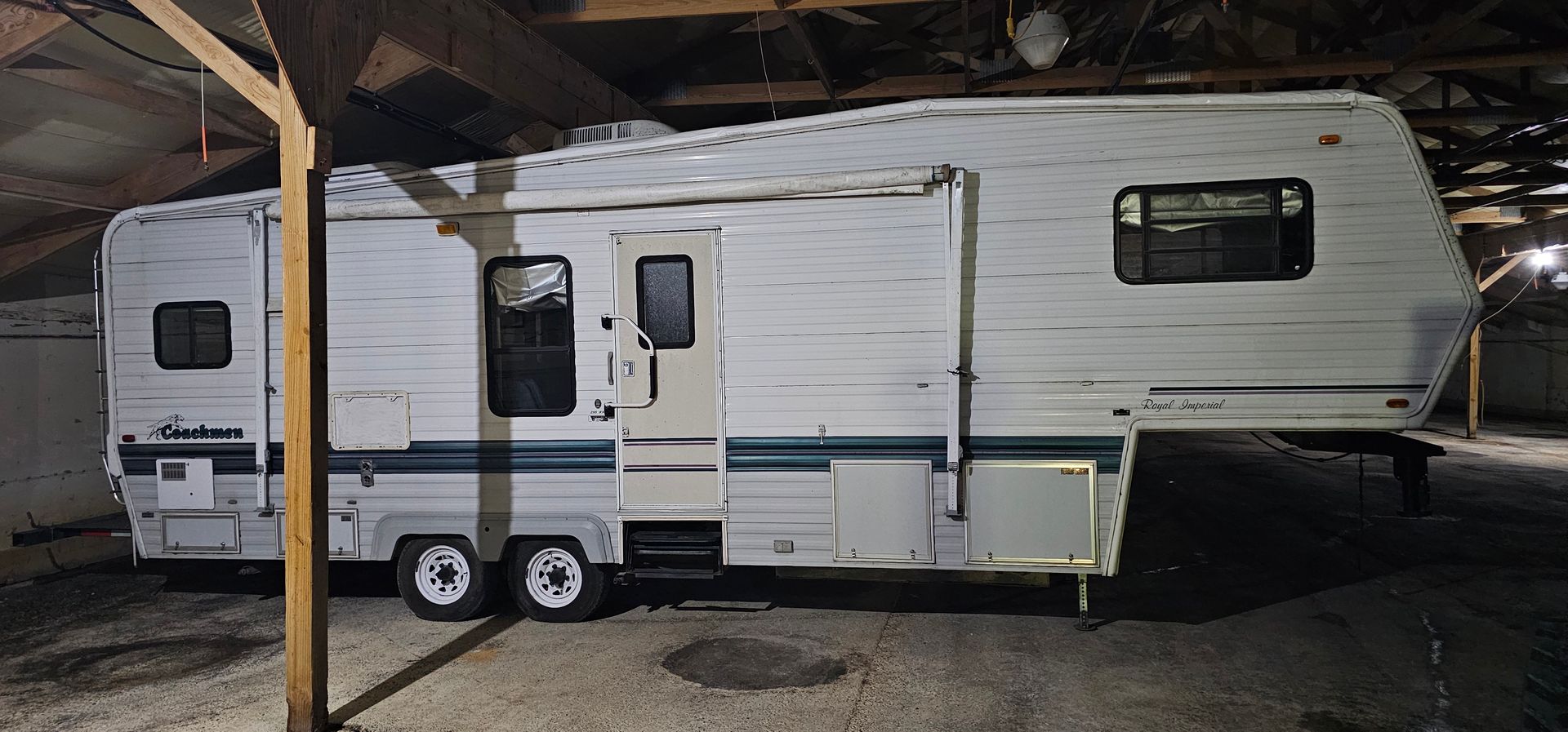 White travel trailer parked under a covered structure at night