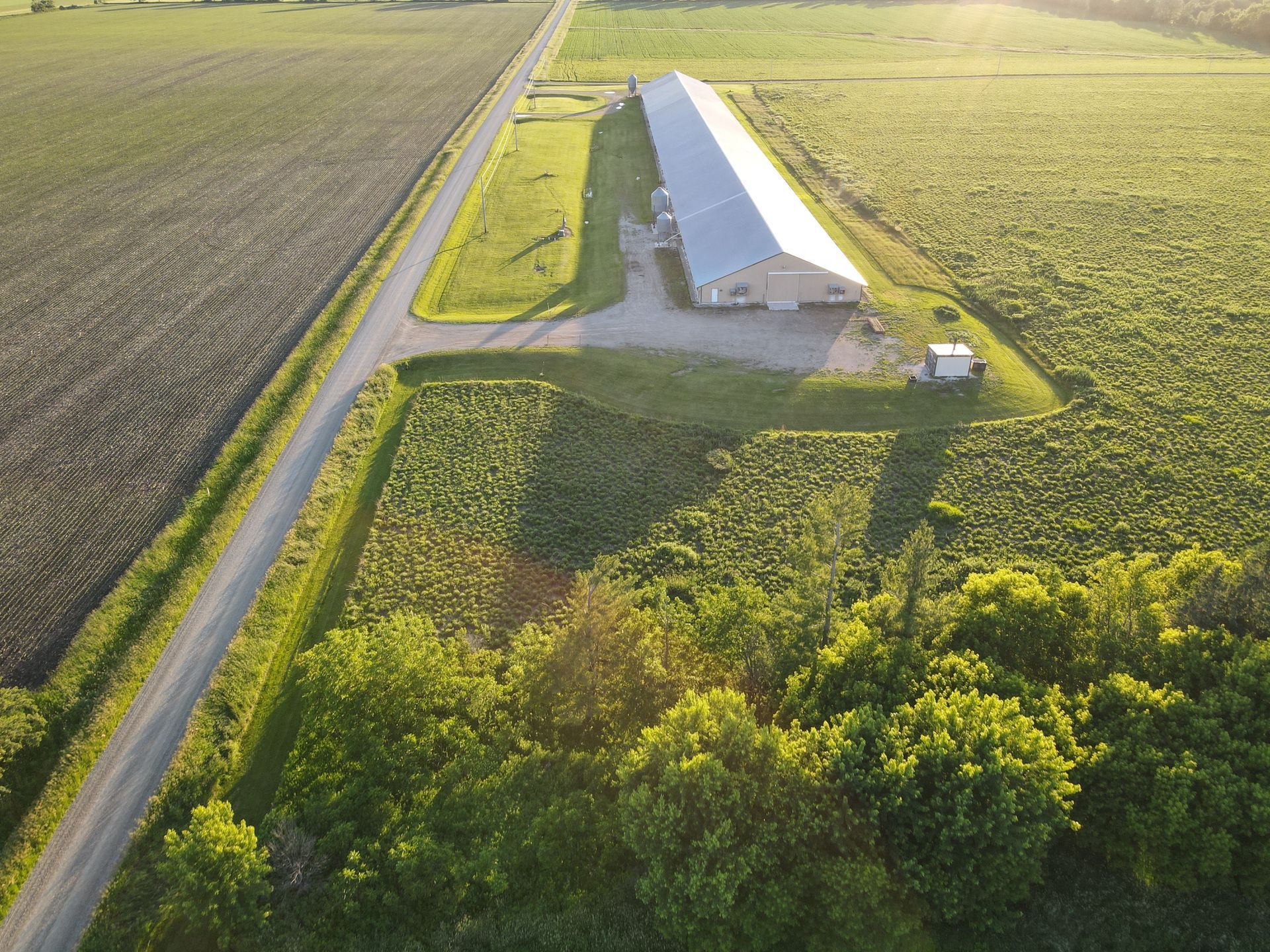 An aerial view of a farm with a white building in the middle of a field.