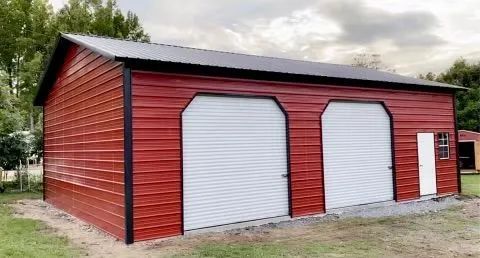 A red garage with two white garage doors and a black roof.