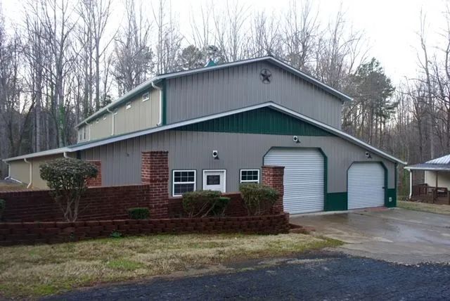 A large metal building with a green roof is sitting next to a house.