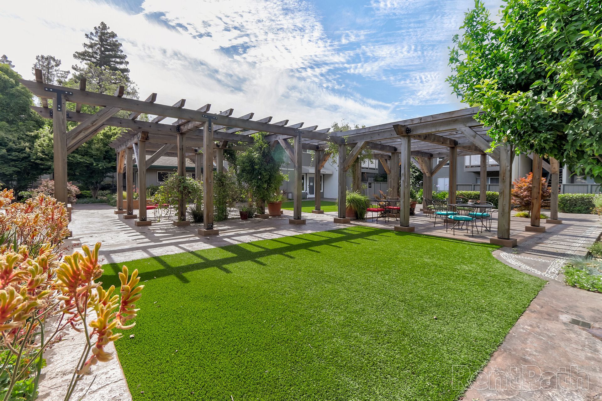 There is a pergola in the middle of a lush green lawn.