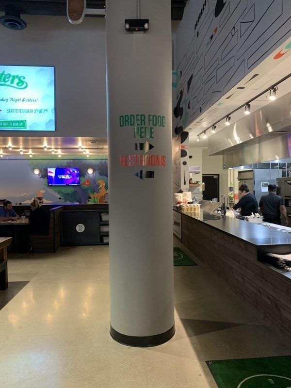 A cylindrical pillar in a restaurant with text directing customers to order food and pick it up.