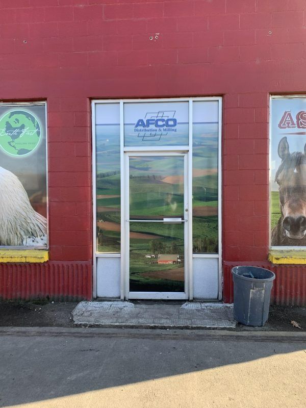 A storefront entry with red walls, glass doors displaying a rural landscape, and advertisements of a horse and a logo.