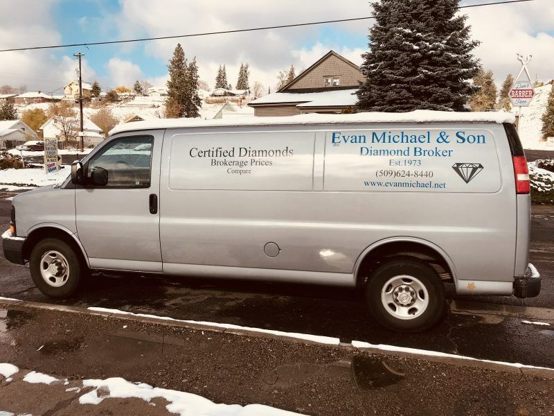 A silver cargo van parked on a snowy street, featuring business signage for 