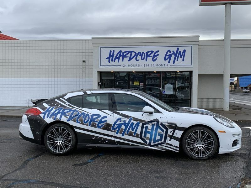 A white, black-accented sports car parked in front of a building with a large 