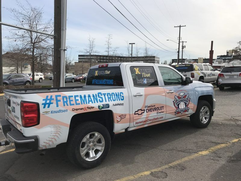 A white Chevrolet pickup truck in a parking lot featuring baseball-themed graphics and the hashtag #FREEMANSTRONG.