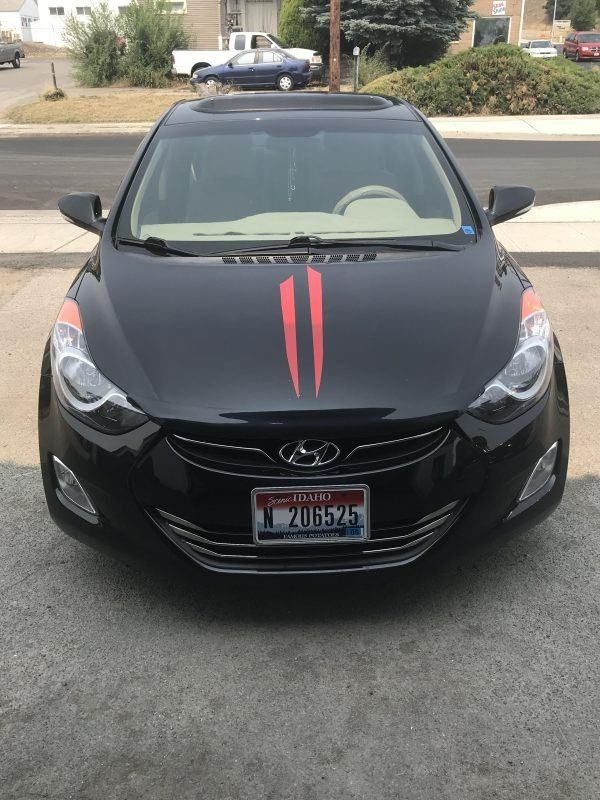 A black Hyundai Elantra parked on a driveway with dual red stripes on the hood.