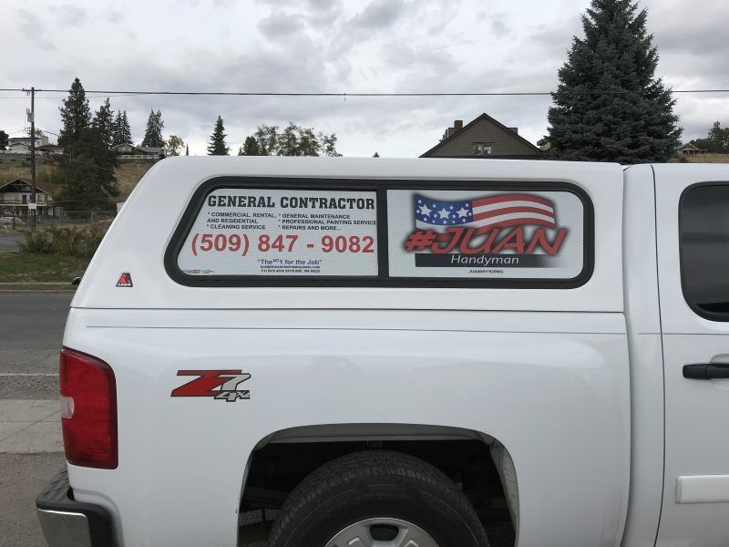 A white truck camper shell with a business advertisement, including a phone number and the text 