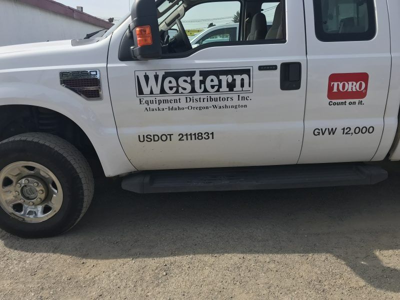 A side view of a white Western Equipment Distributors truck featuring Toro branding and USDOT number 2111831.