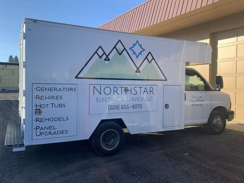 A white Northstar Electric & Service box truck with a mountain and star logo, parked in front of a tan building.