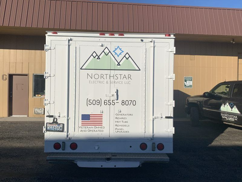 The back of a white Northstar Roofing and Construction box truck parked in front of a tan commercial building.