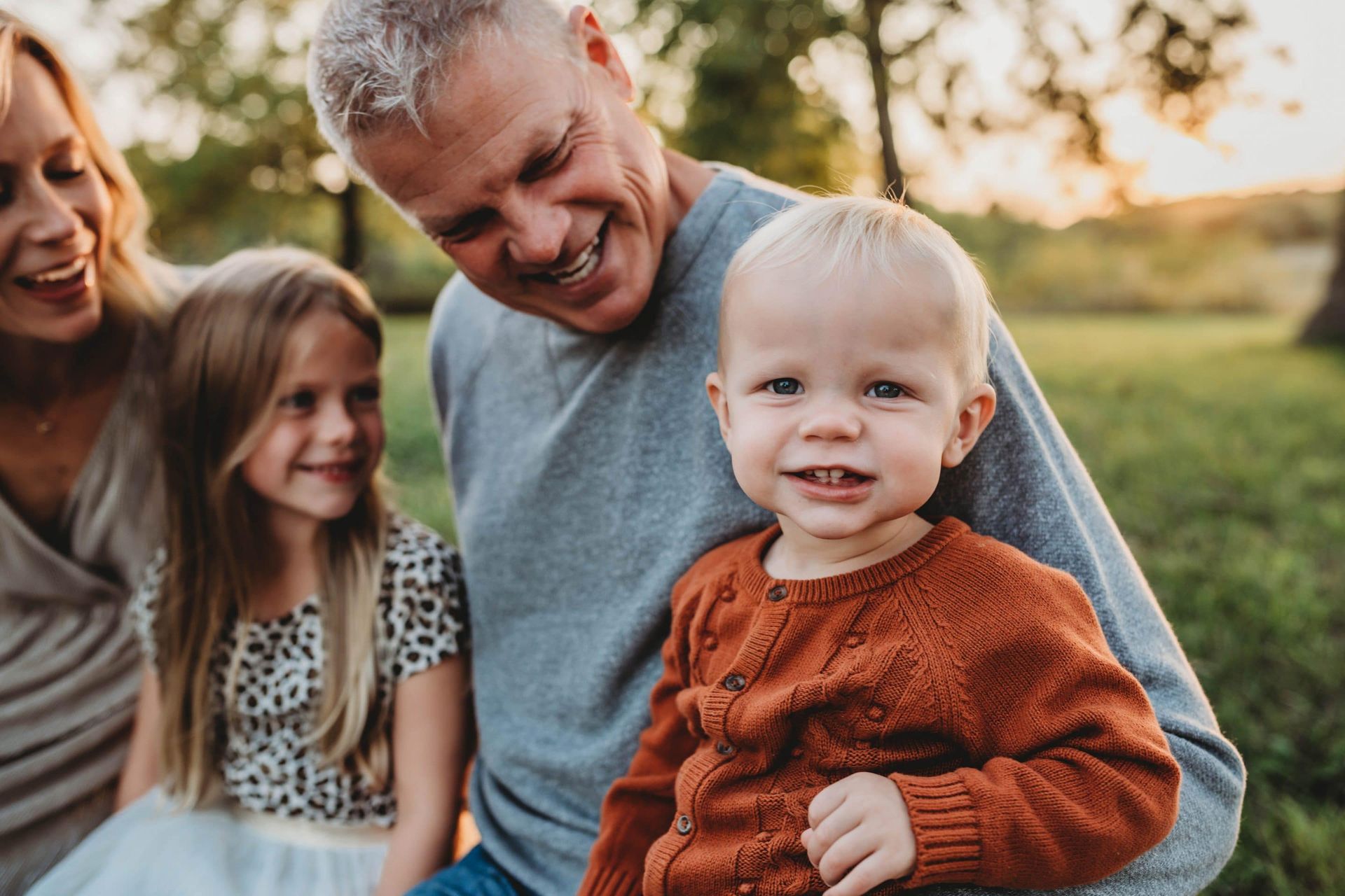 A man is holding a baby while a woman and two children look on.