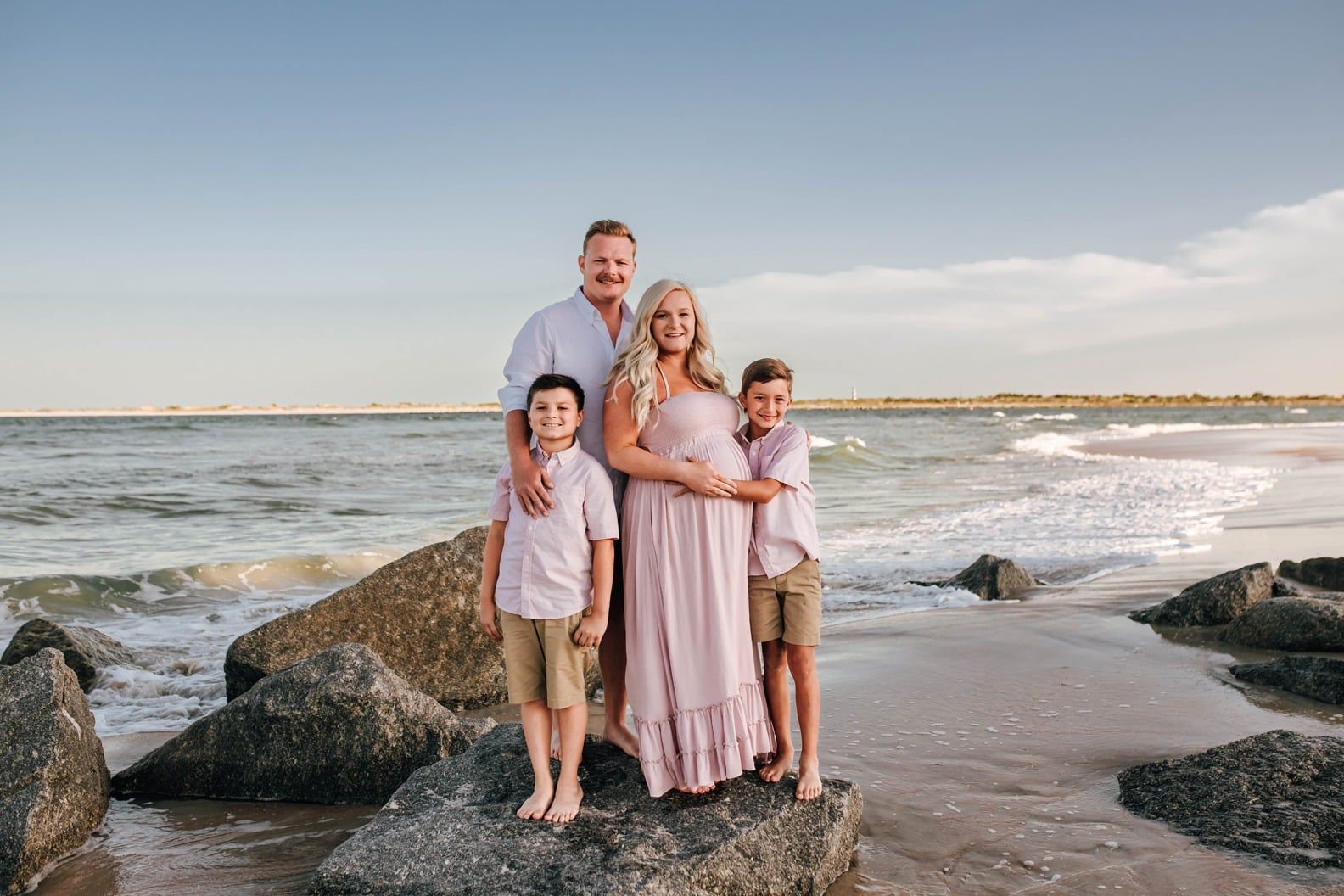 A family is standing on rocks on the beach.