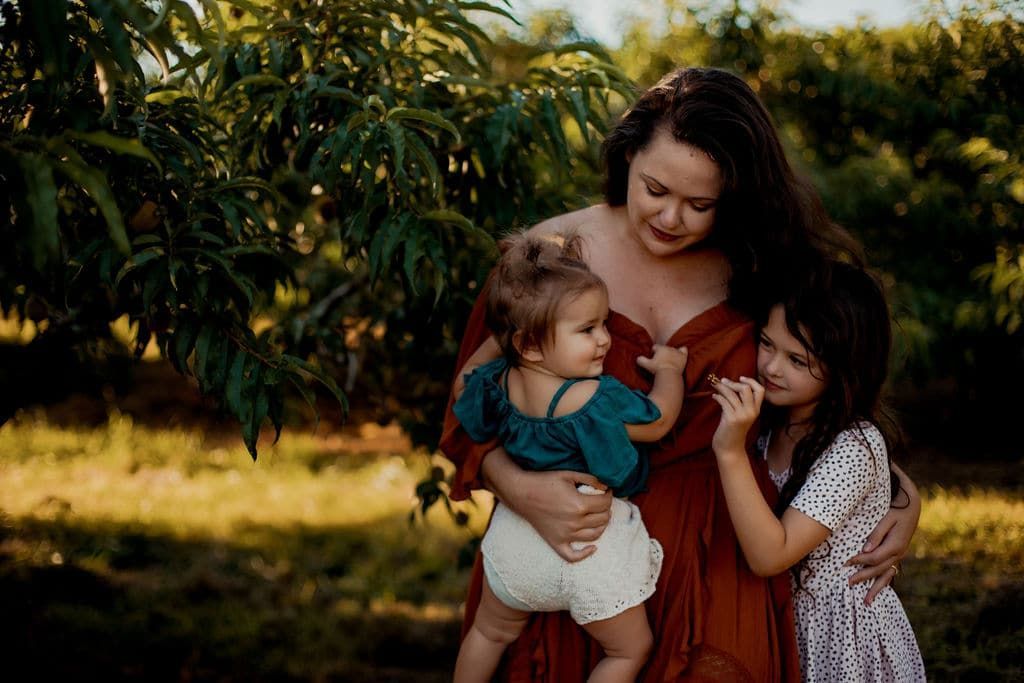 A woman is holding two little girls in her arms.