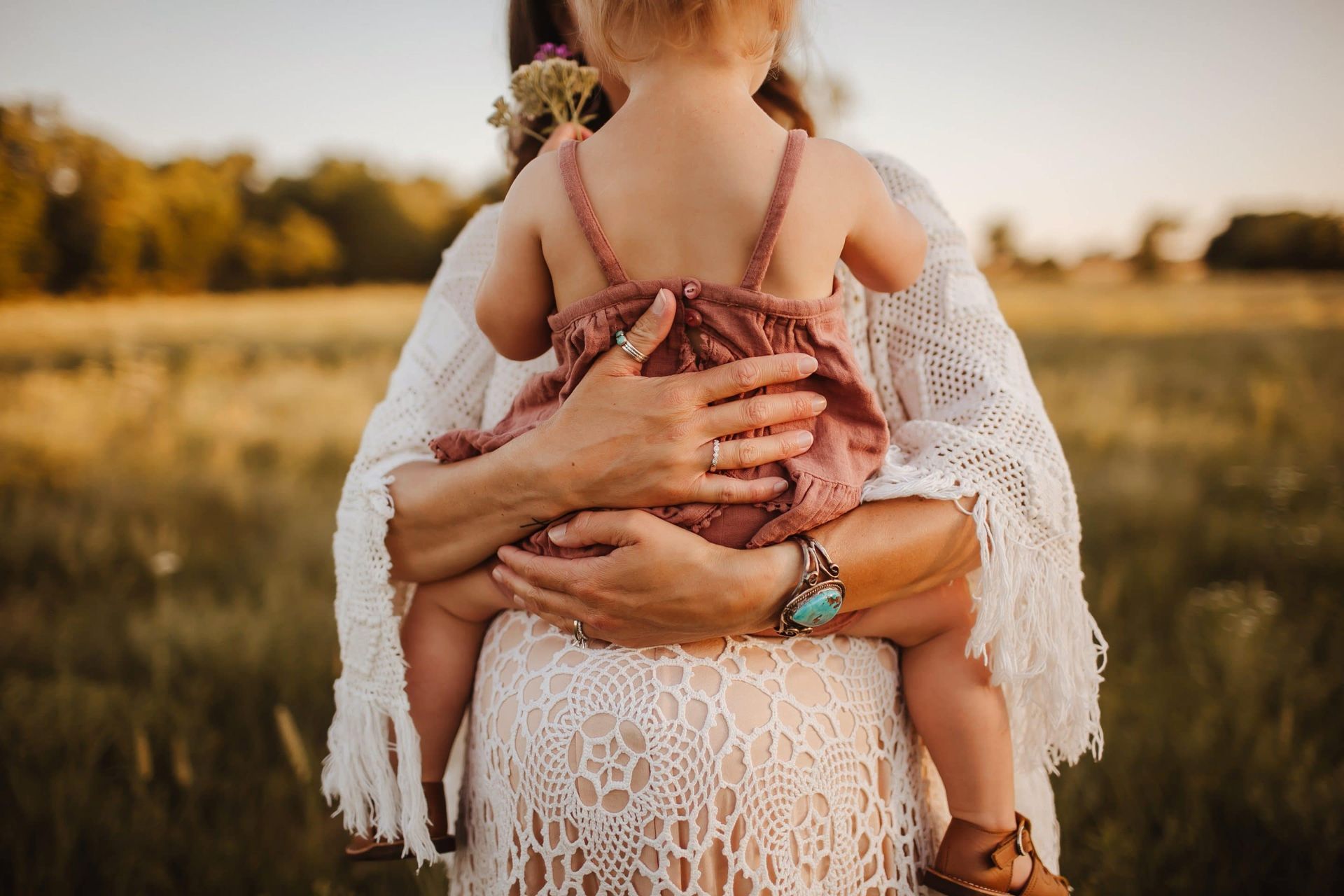 A woman is holding a baby in her arms in a field.