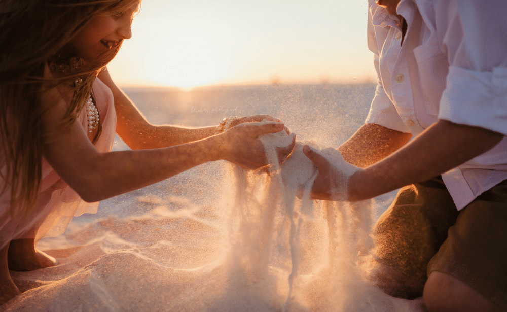 A man and a woman are playing with sand on the beach.