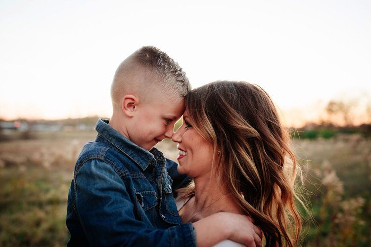 A woman is holding a little boy in her arms in a field.