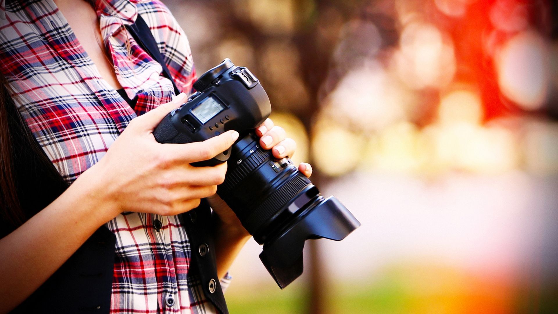 A woman is holding a camera in her hands.